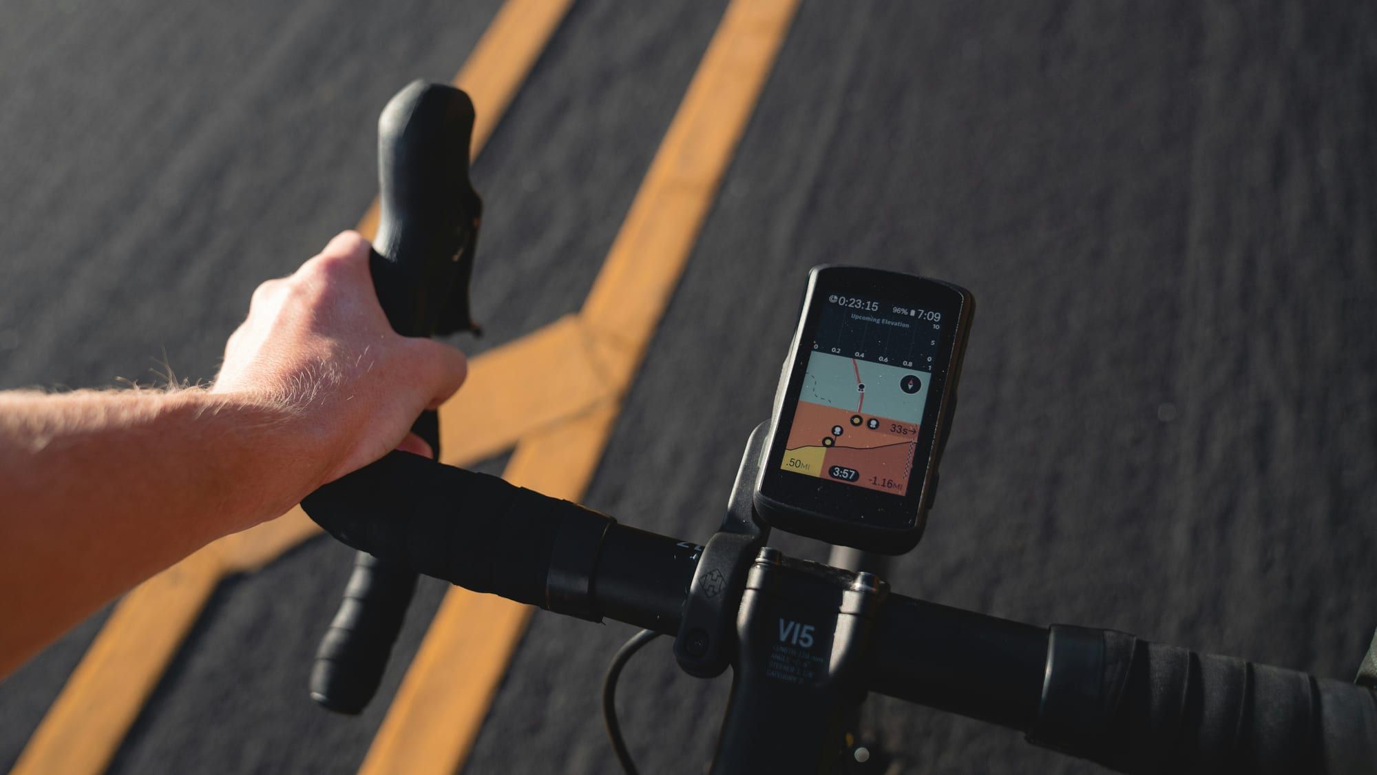 Hånd på styret med en mobiltelefon som viser en sykkelapp