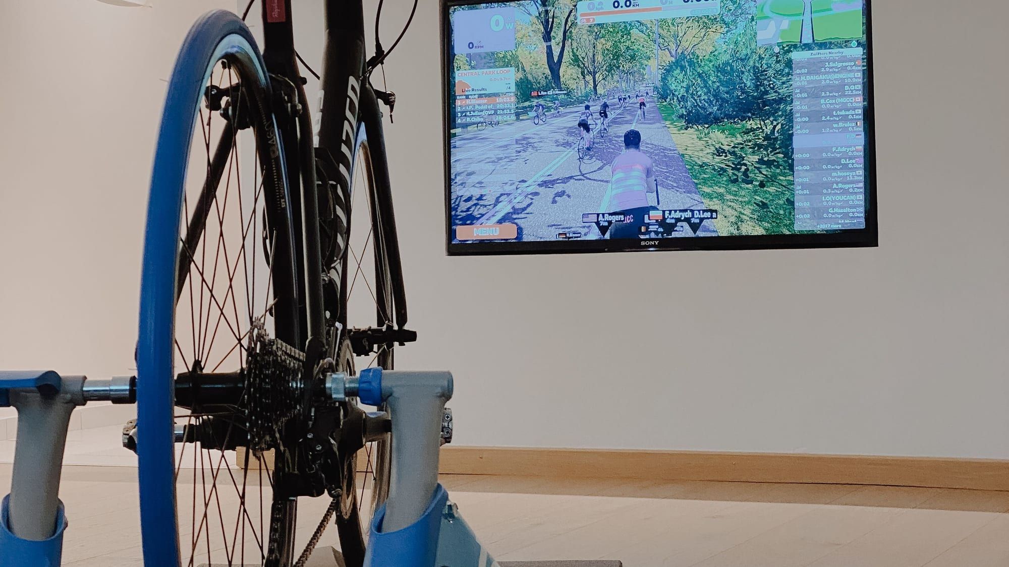 Sykkel på hjulmontert sykkelrulle foran en TV med en virtuell sykkelapp