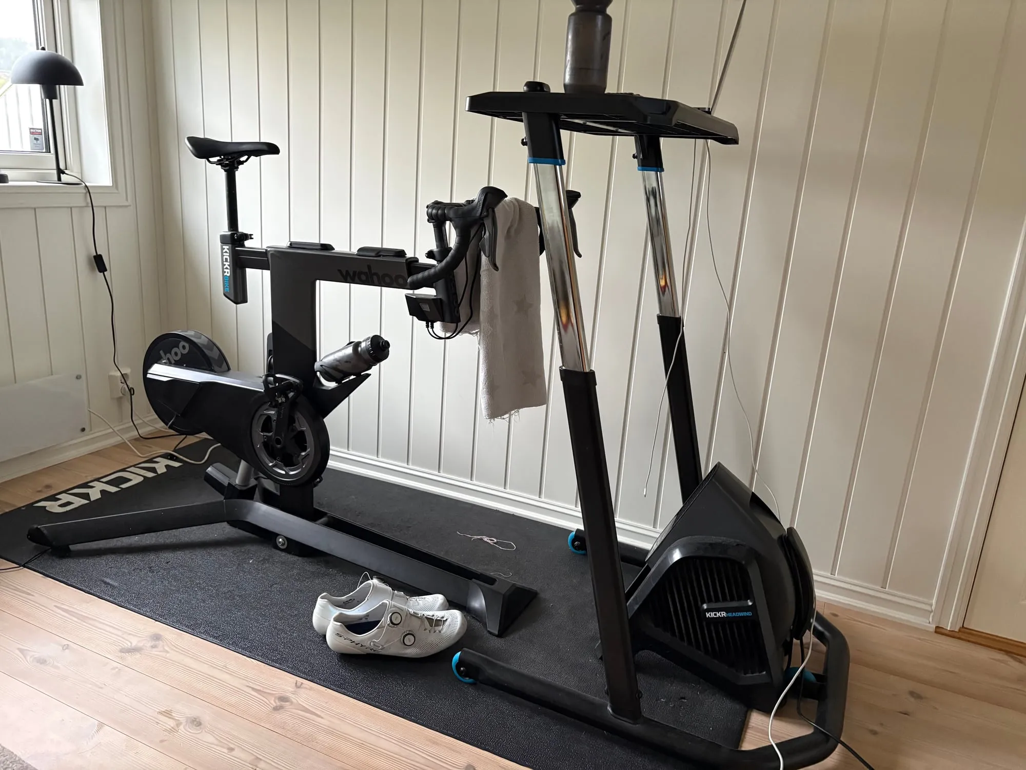 Wahoo-vifte på gulvet rett foran en Wahoo KICKR Bike, som står på en svart treningsmatte