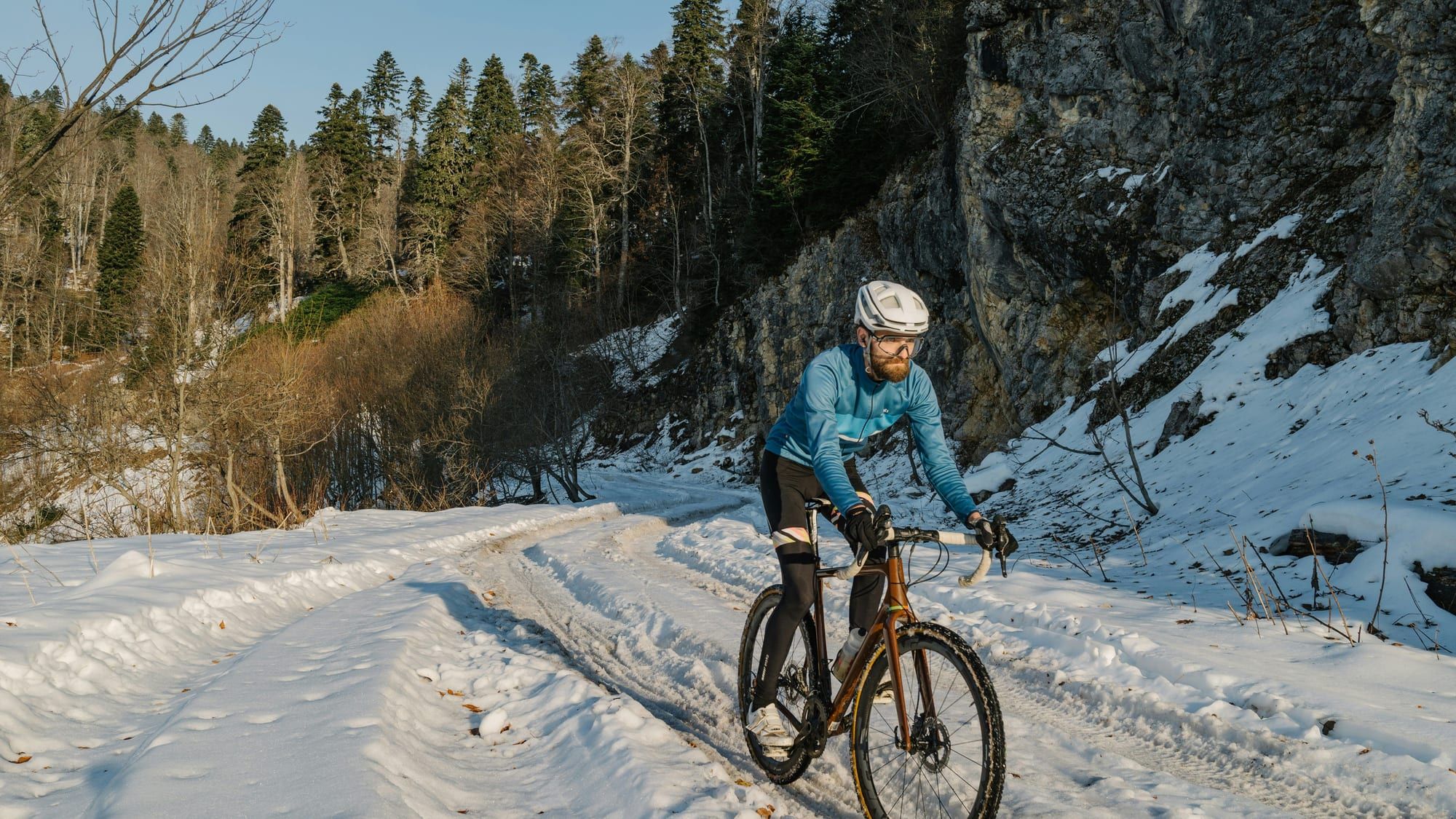 Syklist på en snødekt skogsvei om vinteren